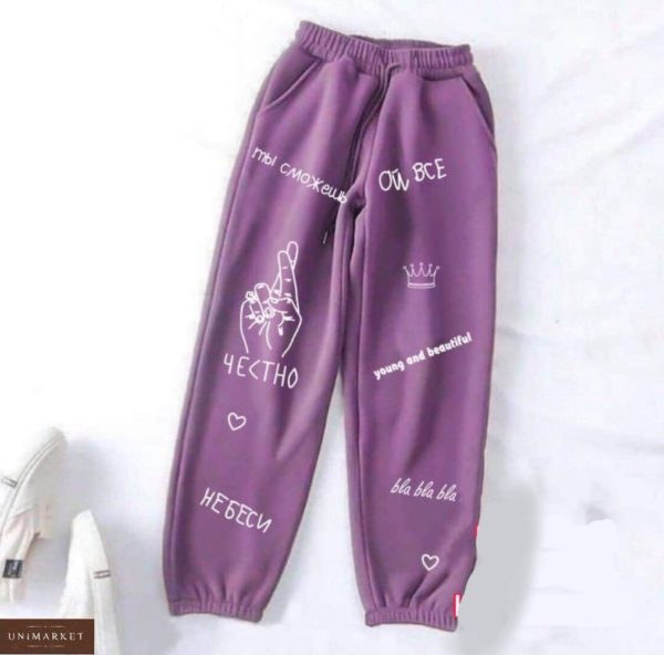 Придбати фіолетового кольору спортивні штани для жінок на гумці з написами по знижці