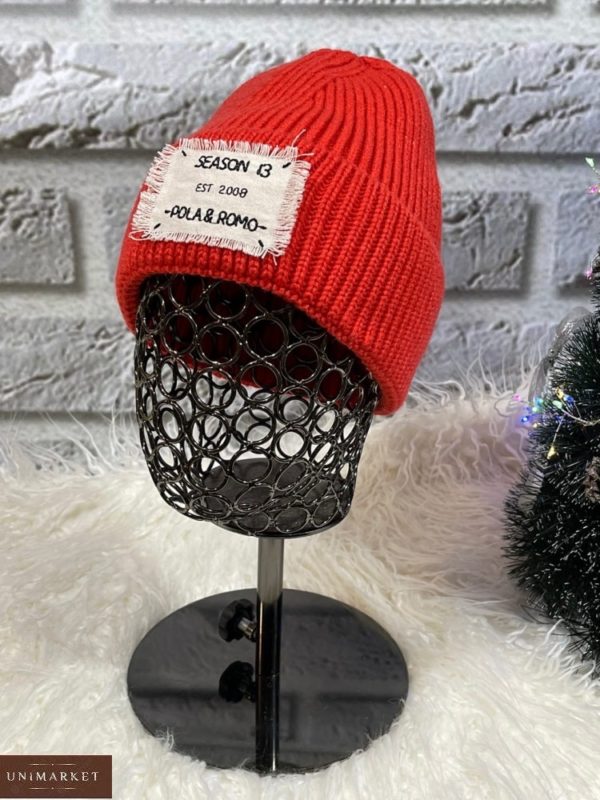 Купити червоного кольору жіночу шапку з нашивкою в Україні